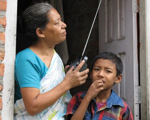 Mother and son stand at doorstep with radio.