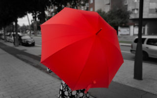 lady standing in the street with red umbrella