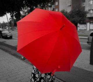 lady standing in the street with red umbrella
