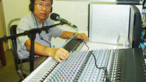 Man sitting in AWR radio studio behind equipment