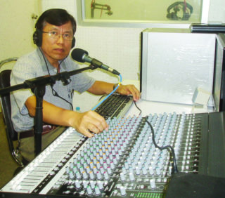 Man sitting in AWR radio studio behind equipment